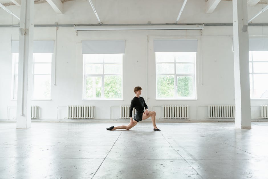 A focused man practicing an arm balance yoga pose in an industrial-style studio.